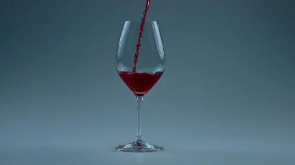 闪闪发亮的葡萄酒喷射玻璃杯特写 松软的酒精液体灌装干净器皿慢动作 发亮的红葡萄酒在酒瓶的白色背景中飞溅 奢华优雅的小贴士概念 — 图库照片
