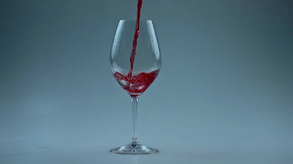 有毒饮料灌满高脚杯慢动作 把酒精液体倒入洁白的酒瓶底 红酒在玻璃杯中形成美丽的波浪 玫瑰射流透明容器壁 — 图库照片
