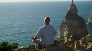Okyanus yamacında yoga gevşemesi uygulayan bir adam. Nilüfer çiçeğinin altında meditasyon yapan kaygısız adam yaz güneşinde poz veriyor. Denizde ilham kaynağı arayan odaklanmış bir maceraperest. Zen denge kavramı gibi