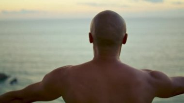 Atlet, güzel okyanus sabahında yoga ruhani egzersizi yapıyor. Tanınmayan kel adam dışarıda üstsüz olarak antrenman yapıyor. Zen yaşam tarzını sever. İç uyum dengesi kavramı