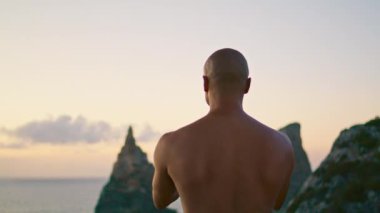 Güçlü bir adam günbatımı okyanus uçurumu manzarasında yoga meditasyonu yapıyor. Sakin ol, konsantre olup namaste hareketi yapan bir adam gibi. Bilinmeyen Yogi ruhani egzersiz yapıyor. İç ahenk dikiz görüntüsü arıyor.