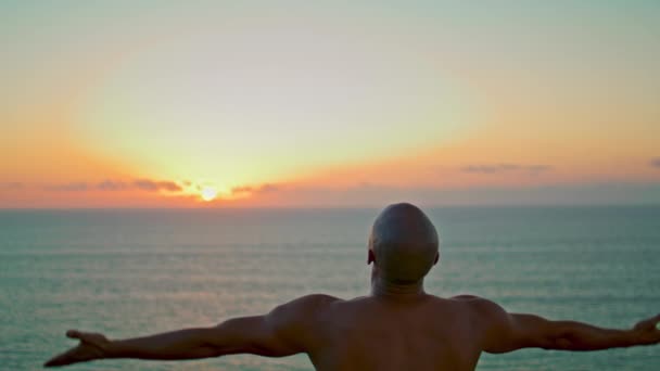 美しい夕日の中でアサナを練習ヨギシルエット 強い男だけで海の日の出で手を上げてリラックス 海で瞑想を集中未知の筋肉運動選手 セレンストレスフリーコンセプト — ストック動画