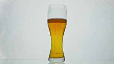 Şeffaf cam, altın birayı çok yavaş çekimde kabarcıklarla doldurdu. Beyaz arka planda kristal kadehte taze alkol içeceği. İçecek olarak demlenmiş malt içeceği..