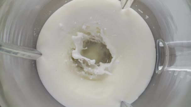 超スローモーションで有機新鮮な牛乳を混合電気ミキサーを閉じます ガラスミキサーボウル内に渦巻く白い乳製品を表示します ミルクシェイクヨーグルトスムージーの天然タンパク質成分 — ストック動画