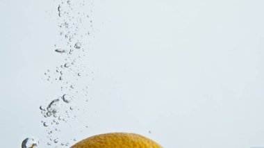 Yakın plan, açık arkaplanda düşen tropikal portakal suyu. Taze yaz meyvesi yüzen kabarcık sıvısı. Sağlıklı organik ürün cam kabın içine sıçrıyor. Güzel yemek reklamı.