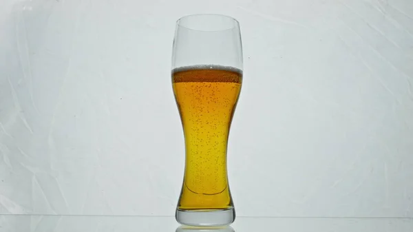 透明ガラスが黄金のビールを満たし 超スローモーションで泡を上げて閉じます 白を基調としたクリスタルゴブレットで新鮮なおいしいアルコール飲料 リフレッシュのための醸造麦芽飲料 — ストック写真