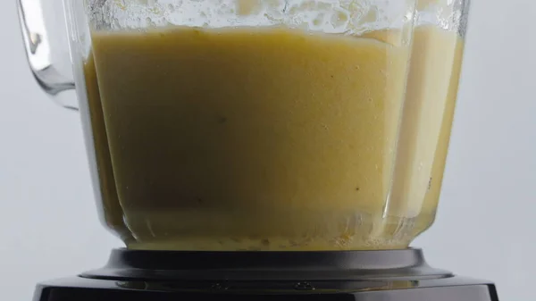 维生素果昔搅拌在搅拌机碗内 动作过慢 收缩压 白色背景的电搅拌器中掺入黄色的天然平滑物质 制备抗氧化剂健康可口的饮料 — 图库照片