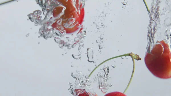 甜甜的成熟樱桃在白色背景下掉进淡水中 五彩缤纷的樱桃滴下清澈的液体 使气泡在超级慢动作中飞溅 有机维生素食品 — 图库照片
