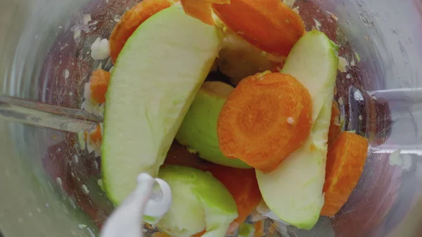 Mixing fresh organic milk with tasty vitamin fruits vegetables in glass blender bowl close up. Dairy liquid pouring in mixer full of apple carrot banana. Process preparing detox healthy cocktail.