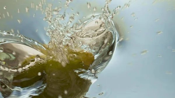Organic lemon splashing water closeup. Beautiful surface reflecting fresh citrus. Tropical fruit falling dropping transparent liquid in light background. Making refreshing summer beverage lemonade