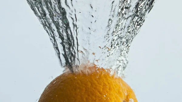 Fresh orange splashing water in light background closeup. Tropical fruit bounce in bubbling transparent liquid. Natural organic product rising surface. Beautiful tranquil commercial for cooking show.
