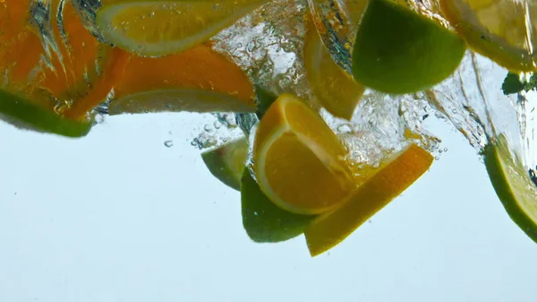 Potongan Buah Jeruk Segar Jatuh Dalam Air Transparan Membuat Percikan — Stok Foto