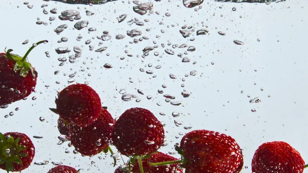 新鲜多汁草莓漂浮透明的水在超级慢动作关闭 红色的甜浆果 有气泡 表面有白底液体 鸡尾酒的味道鲜美成分 — 图库照片