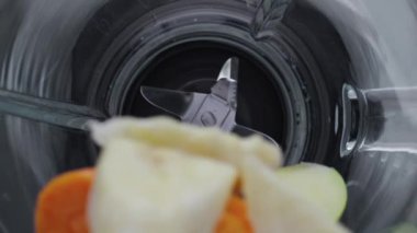 Dilimlenmiş meyve sebzeleri elektrikli blenderi çok yavaş çekimde yakın çekimde düşürdü. Taze olgun elma havucu, muz düşerken mikser kasesi üst görüntüsü. Vejetaryen için doğal vitamin kokteyli hazırlama süreci.