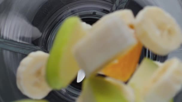 在电动搅拌机顶部视图中添加新鲜有机水果块的遮盖物 香蕉味苹果橘子在超级慢动作下降搅拌器碗 健康维生素鸡尾酒的天然成份 — 图库视频影像