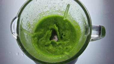 Yeşil vejetaryen karışımı elektrikli miksere karıştırıp üst manzarayı kapatın. Vejetaryen taze smoothie karışımı cam karıştırıcı süper yavaş çekimde. Meyve sebzelerinden nefis vitamin kokteyli..