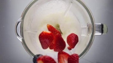 Taze olgun çilek, milkshake ve elektrikli mikserle harmanlanmış yaban mersini ve nar tohumları dökülüyor. Lezzetli vitamin böğürtlenleri süte çok yavaş düşüyor. Mandıra meyveli kokteyli.