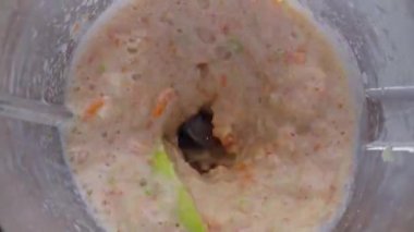 Meyve karışımı karıştırma kabında hazırlanıyor. Üst tarafı kapatın. Lezzetli vitamin içeceği için mutfak aletlerine karıştırılmış sulu elma havucu. Doğal organik püre süper yavaş çekimde mikserin içinde dönüyor..