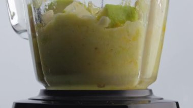 Karışık lezzetli meyve karışımı karıştırıcı cam kasenin içinde. Kapatın. Dilimlenmiş vitamin bileşenleri elektrikli mikserde harmanlanıyor süper yavaş çekimde. Organik vejetaryen yemekleri karıştırıyorum. Sağlıklı beslenme.