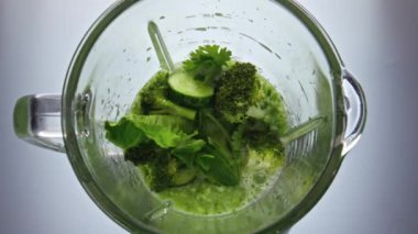Elektrikli blender taze sebze sebzelerini karıştırmaya başlıyor. Üst manzarayı kapatıyor. Salatalık avokado kereviz elmalı maydanoz süper yavaş çekimde harmanlanıyor. Ev yapımı sağlıklı vitamin hazırlıyorum..