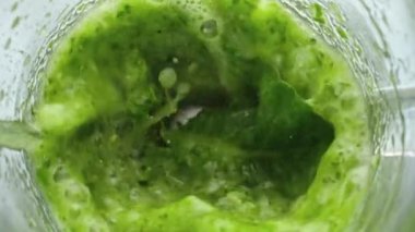 Sebze suyu ve sebze meyvesi hazırlamanın en iyi manzarası. Yeşil smoothie yüzeyi, cam blender içinde çok yavaş çekimde fokurduyor. Ham vitamin sebzelerini karıştıran elektrikli mikser..