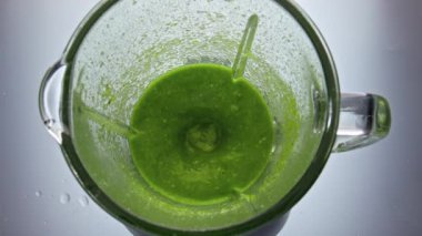 Kapalı yeşil smoothie elektrikli blender süper yavaş çekimde hazırlanıyor. Sebzelerden taze bir karışım cam karıştırıcıya karıştırılmış meyve sebzeleri. Sağlıklı yaşam tarzı için lezzetli vitamin kokteyli..