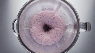 Elektrikli blender kasesine karıştırılmış meyveli kokteyl. Süper yavaş çekimde. Üst görünüm meyveli süt karışımı mikserin içine sıçrıyor. Pembe doğal yoğurt organik malzemelerden hazırlanır. Sağlıklı yemek..