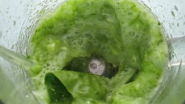 Blender kasesinde dönen yeşil vegan kokteylinin en üst görüntüsü. Taze çiğ sebzeler. Meyve sebzeleri. Elektrikli karıştırıcıyı süper yavaş çekimde karıştırıyor. Ev yapımı sağlıklı vitamin yemekleri..