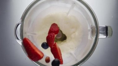 Lezzetli organik böğürtlenler elektrikli mikserde taze süte dökülüyor. Ev yapımı yoğurt hazırlamak için beyaz süt ürünlerine çilek ekliyorum. Doğal yemek pişirmek..