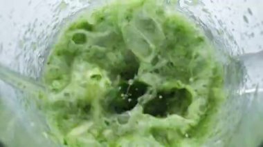Sebzelerle karıştırılmış sebzeler blender kasesinde. Yakın çekim. Taze yaprak lahana maydanoz karıştırıcı cam karışımı süper yavaş çekimde. Yeşil vitamin karışımı köpüklü üst görünüm. Vejetaryen beslenme konsepti.