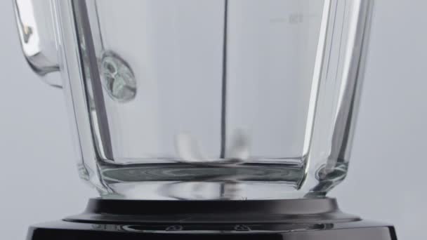 闭合金属搅拌机叶片在空玻璃碗内旋转 动作非常缓慢 电动搅拌机在没有食物的白色背景下工作 配餐用的现代厨房用具 — 图库视频影像