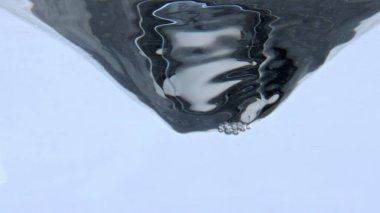 İçecek girdabı teknenin içinde dönüyor, yakın plan. Temiz sıvı fırıl fırıl dönüyor. Çok yavaş çekimde. Taze su içme girdabı beyaz arka plan. Soğuk kokteyl hunisi. Susuzluk kavramı