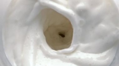 Laktoz içeceği kıvrımlı, hareketli üst manzara. Temiz süt yavaş çekimde dönüyor. Taze süt sıvısı girdabı ve yakın çekim dalgaları. Lezzetli milkshake kokteyli hunisi. Kremalı kalsiyum içeceği girdap