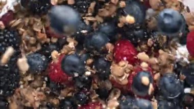 Kahvaltı kasesi granola müsli üst manzara. Süt kremalı sıvıya dökülen lezzetli malzemeler. Lezzetli yulaf ezmeli yoğurt içinde organik böğürtlen sütlü çikolata süper yavaş çekim. Sağlıklı gıda konsepti