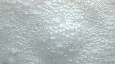 Köpüklü laktoz içeceği yüzey manzarası. Beyaz kabarcıklar yavaşça yaklaşıyor. Sağlıklı süt sıvısı köpürme dokusu kuruluyor. Makro maytaplı süt ürünü kalsiyum likörü. Pastörize içecek konsepti 