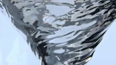 Soğuk cin, konteynırın içinde huni yapıyor. Taşıyıcı içinde dönen şeffaf tonik kokteyl. Cam kadehte buzlu su kolonu. Dönen sıvı tornado ağır çekimde taze içecek bardağı. 