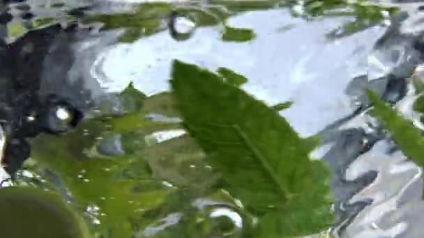 クリーンなガラスの中で回転する固定ミントカクテル 透明な容器に滴が回転して輝くビタミン水 マクロビューの白い表面の背景 夏の新鮮な冷たい飲み物のコンセプト — ストック動画