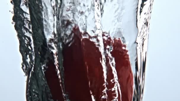 秋の桃の水のガラスを閉じます マクロで全体熟した果実と冷たいアクア 透明な泡容器でおいしい製品 赤いポム液体の遅い動きに没頭 ベジタリアンフードコンセプト — ストック動画