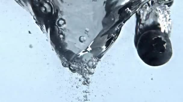 液体ベリーをデトックス渦巻くきれいな容器を閉じます 透明なガラスをゆっくりと動く透明アクア 気泡の白い背景を持つブルーベリー渦の水 アイス炭酸カクテル漏斗 — ストック動画