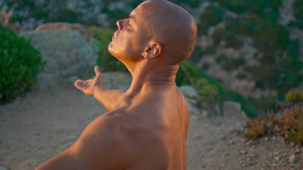 Meditating man relaxing beach in sunlight closeup. Muscular male back arms stretching. Bald athletic guy practicing yoga asana in sunset topless. Spiritual harmony balance. Zen like lifestyle concept.