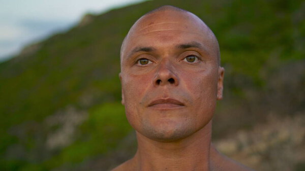 Man practicing spiritual yoga training portrait. Focused calm yogi meditating relaxing outdoors in morning. Athletic bold guy concentrating at green mountain landscape. Zen like mindfulness concept.