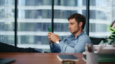 Ciddi patron panoramik bir yerde akıllı telefonda çalışıyor. Modern ofiste cep telefonu kullanan odaklanmış bir işadamı. Lüks iş yerinde düşünceli bir çalışanın cep telefonuna mesaj atması. Teknoloji konsepti 