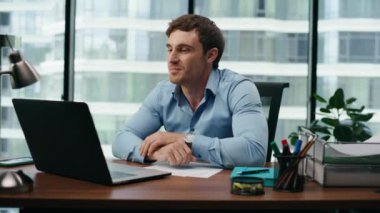 Genç ve mutlu bir adam, iş molasında çocuğuyla görüntülü konuşuyor. Ofis masasını kapatın. Çekici gülümseyen adam, çocukla bilgisayarla iletişim kuruyor ve peekaboo oynuyor. Modern hayatta teknoloji..