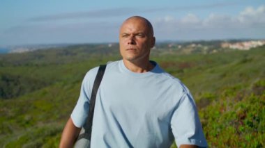 Yogacı adam gün ışığında dışarı çıkıyor. Okyanus manzaralı yeşil alanda yürüyen odaklanmış bir adam. Huzurlu atletik yogi idmandan sonra deniz kayalıklarında doğanın tadını çıkarıyor. Yalnızlık yaz rahatlama konsepti.