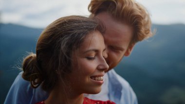 Aşk çifti yaz tatilinde dağlarda mutlu hissediyorlar. Kızıl saçlı adam ve kadın dışarıda şefkat gösteriyorlar. Doğada birbirini okşayan gülümseyen aşıkların portresi. Romantik balayı zamanı