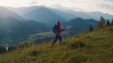 Woman climb hike mountains. Active backpacker walk nature green hill at sunrise. Alone girl enjoy weekend leisure on summer vacation. Trekker travel on majestic scene landscape. Wanderlust concept.
