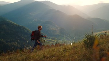 Strong man climb mountains hill nature. Walking tourist enjoy hike on vacation. Young hipster guy backpacking using trekking poles on summer recreation. Outdoors activity healthy lifestyle concept.
