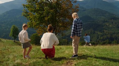 Relaxed family spending time on summer nature with pedigree pet. Back view of young woman with children looking on red hair man walking fluffy dog outdoors. Friendly people enjoying sunny day together