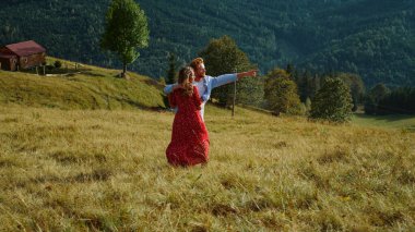 Romantic couple walk mountains nature outdoors. Happy family enjoy summer travel. Two young people relax on green hill. Cheerful lovers look landscape view on vacation. Leisure lifestyle concept.