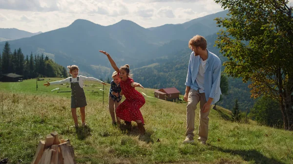 Smiling Family Playing Showing Funny Poses Green Hill Cheerful Parents — Zdjęcie stockowe